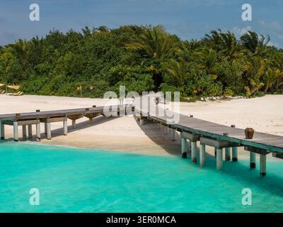 Holzpier zum Sandstrand und den Palmen auf einer Malediven Resort Insel Stockfoto