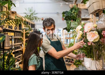 Mitarbeiter im Gartencenter arrangieren Blumen und Pflanzen Stockfoto