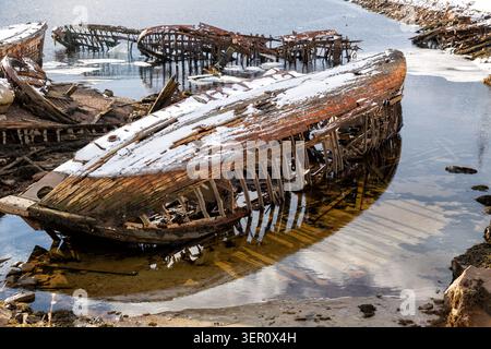 Friedhof alter Boote am Ufer der Barentssee in Teriberka bei Ebbe. Region Murmansk, Russland Stockfoto