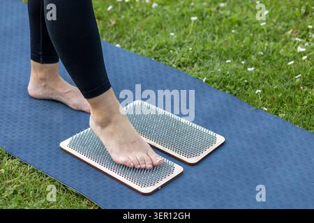 Frau, die auf Sadhu-Brett während der Wellness-Praxis im Freien steht Stockfoto