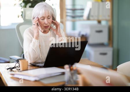 Ältere Geschäftsfrau leidet während der Arbeit im Büro unter Kopfschmerzen Stockfoto