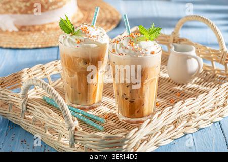 Leckerer und kalter Eiskaffee serviert mit Glas und Strohhalm. Latte mit süßer Sahne. Stockfoto