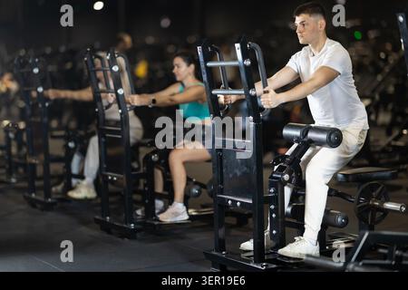 Ein Typ, der im Fitnessstudio auf dem Gerät sitzende Widerstandsübungen durchführt Stockfoto