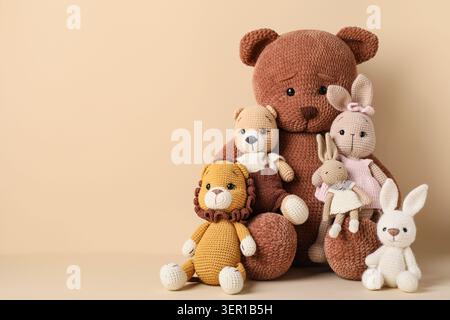 Auswahl an handgefertigten, gehäkelten Stofftieren, darunter ein großer Bär, ein kleiner Löwe und Hasen für Kinder und Kinderzimmer Stockfoto