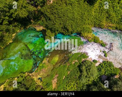 Blick aus der Vogelperspektive auf die Blue Eye Quelle mit ihrem kristallklaren türkisfarbenen Wasser und der lebendigen grünen Vegetation in Finiq, Vlore County, Albanien. Stockfoto