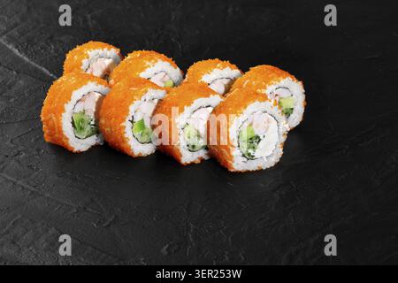 Köstliche frische kalifornische Uamaki-Sushi-Brötchen mit Garnelen, Avocado, Gurke, Frischkäse und Tobiko auf einem schwarzen Schieferteller Stockfoto