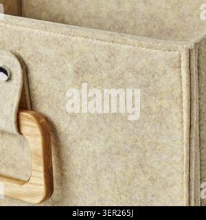 Nahaufnahme einer beigefarbenen Filzbox mit leichtem Holzgriff, die die weiche Textur des Filzmaterials unterstreicht Stockfoto