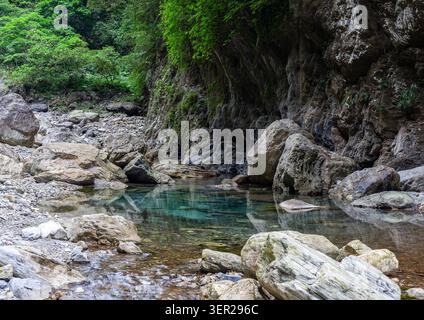Sanzhanxi-Flussbecken im Taroko-Nationalpark, Taiwan. Klares türkisfarbenes Wasser fließt durch eine felsige Schlucht. Üppig grüne Vegetation bedeckt steile Klippen. Stockfoto
