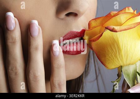 Nahaufnahme des unteren Teils des Mädchengesichts mit gelber Rose Stockfoto