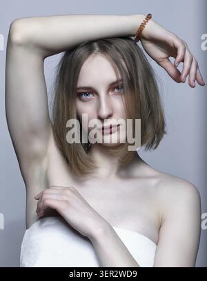 Nahporträt der schönen jungen blonden Frau. Eine Frau mit erhobener Hand schaut in die Kamera Stockfoto