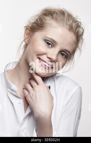 Emotionales Porträt einer jungen blonden Frau auf grauem Hintergrund. Weibliche lächelnd und Suchen in der Kamera Stockfoto