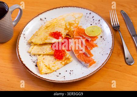 Dünne Pfannkuchen mit Kaviar und Lachs auf einem Teller Stockfoto