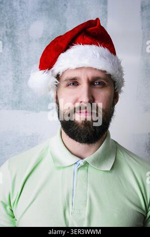 Weihnachtsfeierporträt eines jungen Erwachsenen bärtigen glücklichen Mannes mit Weihnachtsmütze Stockfoto