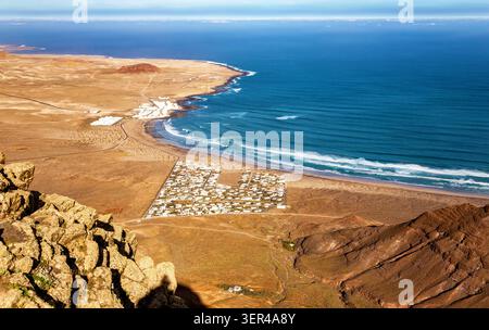 Dorf Caleta de Famara, Insel Lanzarote, Kanarische Inseln, Spanien, Europa. Küstenlandschaft vom Aussichtspunkt Mirador de El Risco de Famara aus gesehen. Stockfoto