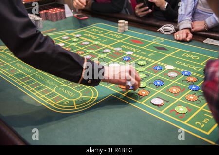 Casino, Glücksspiel und Unterhaltung Konzept - Roulette Tisch und Stapel von poker chips Stockfoto