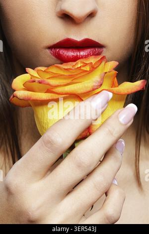 Nahaufnahme des unteren Teils des Mädchengesichts mit gelber Rose Stockfoto
