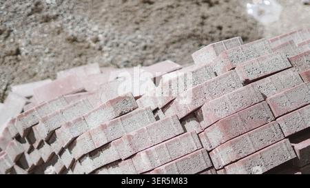 Rote Betonpflastersteine, die nahe auf dem Boden gestapelt sind. Stockfoto