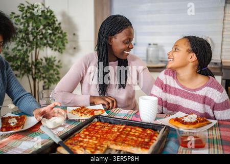 Fröhliche Familie, die hausgemachte Pizza zu Hause genießen Stockfoto