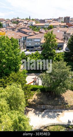 Allariz Stadt mit traditionellen Dächern, grünen Bäumen und Kinderspielplatz von einem erhöhten Aussichtspunkt an einem klaren Sommertag Stockfoto