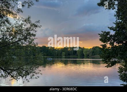 Idyllischer Sonnenuntergang an einem Teich mit Weidenbäumen, die sich im ruhigen Wasser spiegeln Stockfoto
