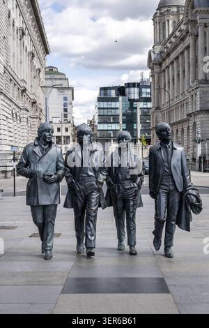 Blick auf die Beatles Statue mit den Bronzestuppen der Bandmitglieder, die auf dem Pier Head entlang spazieren gehen, umgeben von historischer Architektur Stockfoto