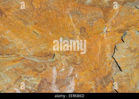 Detaillierte sedimentäre Gesteinsoberfläche mit Rissen und orangen Eisenoxidmustern in Berggebieten in Kirgisistan Stockfoto