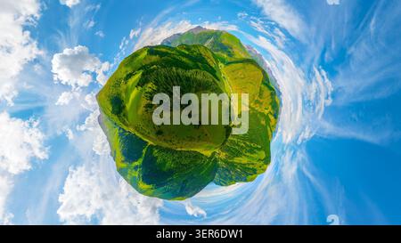 Der Blick auf den kleinen Planeten aus der Vogelperspektive fängt üppige grüne Berge und Täler unter hellen weißen Wolken ein. Pulsierende Landschaft mit sanften Hügeln und Stockfoto