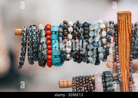 Verschiedene Kollektion von lebendigen Armbändern mit Perlen, die auf einem rustikalen Holzständer an einem Marktstand zum Verkauf stehen Stockfoto
