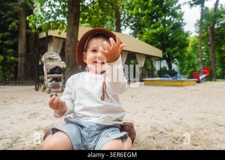 Kleinkind in Sun hat im Sandy Playground Park Stockfoto