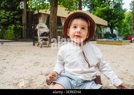 Kleinkind in Sun hat im Sandy Playground Park Stockfoto