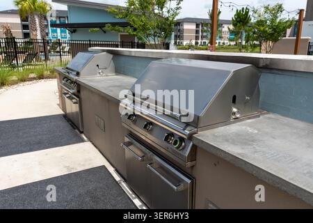 Außenküche in einem modernen Wohnkomplex mit eingebauten Edelstahlgrills mit mehreren Brennern und unteren Ablagefächern Stockfoto