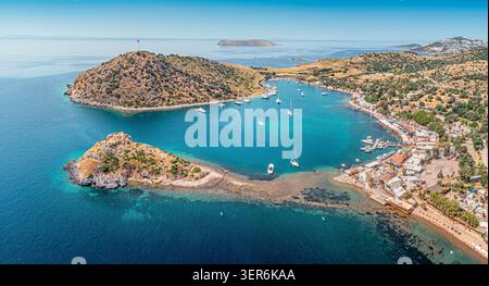 Gumusluk, Bodrum, genießt einen warmen Sommertag und zeigt Rabbit Island und private Yachten, die in der klaren türkisfarbenen Ägäis ankern Stockfoto