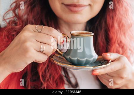 Eine Frau hält eine Tasse türkischen Kaffee, entspannt und genießt den Moment. Hände mit Ringen, die die Tradition umschmeicheln Stockfoto
