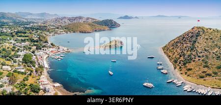 Gumusluk, Bodrum, genießt einen warmen Sommertag und zeigt Rabbit Island und private Yachten, die in der klaren türkisfarbenen Ägäis ankern Stockfoto