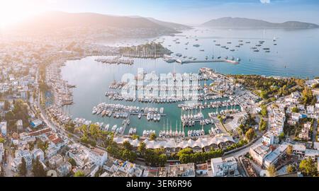 Aus der Vogelperspektive von Bodrum, Türkei, zeigt den Hafen voller Boote und Yachten und die umliegenden Gebäude der Stadt unter einem warmen Sonnenuntergang Stockfoto