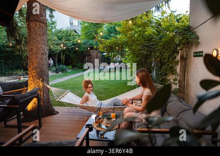 Zwei junge Frauen, die sich im Garten-Café unterhalten Stockfoto