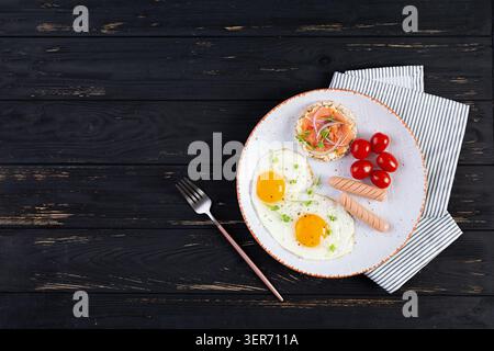 Spiegeleier mit Wurst, Kirschtomaten und Buchweizenbrot mit Lachsfisch Stockfoto