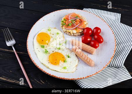 Spiegeleier mit Wurst, Kirschtomaten und Buchweizenbrot mit Lachsfisch Stockfoto