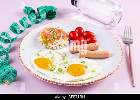 Spiegeleier mit Wurst, Kirschtomaten und Buchweizenbrot mit Lachsfisch Stockfoto
