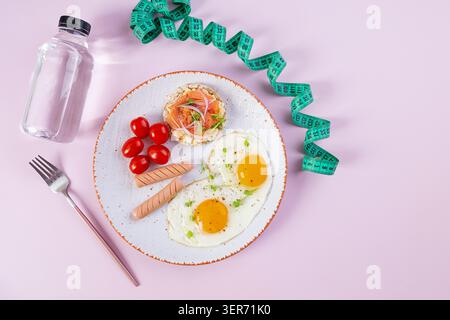 Spiegeleier mit Wurst, Kirschtomaten und Buchweizenbrot mit Lachsfisch Stockfoto