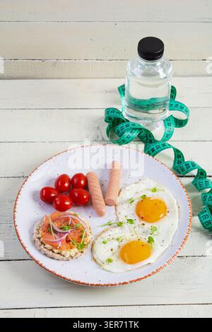 Spiegeleier mit Wurst, Kirschtomaten und Buchweizenbrot mit Lachsfisch Stockfoto