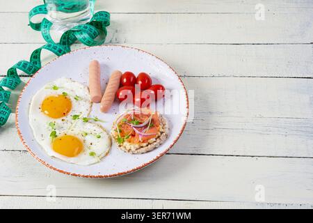 Spiegeleier mit Wurst, Kirschtomaten und Buchweizenbrot mit Lachsfisch Stockfoto