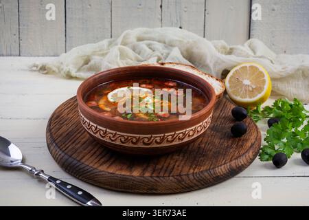 Schüssel mit traditioneller Soljanka-Suppe mit gemischtem Fleisch und Oliven. Herzhaftes, hausgemachtes osteuropäisches Gericht Stockfoto