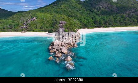 Atemberaubender Drohnenblick auf majestätische Granitfelsen, die das kristallklare türkisfarbene Wasser und den unberührten weißen Sand von Grand Anse und Petite Anse Beach trennen Stockfoto
