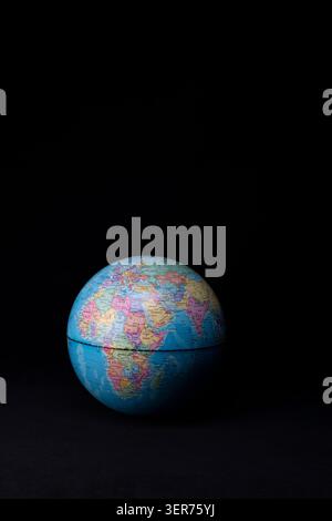 Globus mit politischer Karte und Weltgeographie vor schwarzem Hintergrund Stockfoto