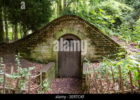Ein altes Backsteineishaus, das 1743 für das Lydiard Park House Swindon in einem Waldgebiet mit einer Holztür erbaut wurde Stockfoto