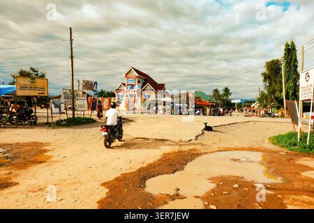 Dirt Road und Straßenszene mit Motorradfahrer in Kyela Town, Tansania Stockfoto