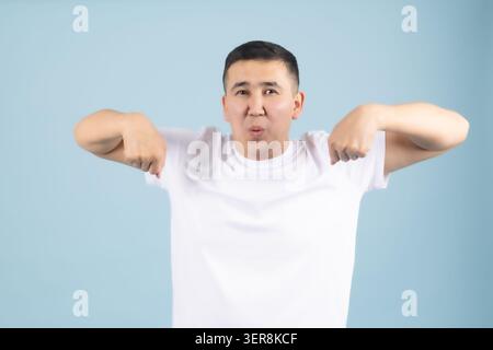 Junger Mann, der mit beiden Zeigefingern nach unten zeigt Stockfoto
