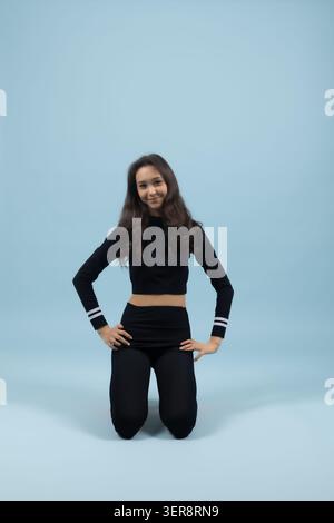 Schöne junge Frau, die in aktiver Fitnessposition auf dem Boden kniet Stockfoto