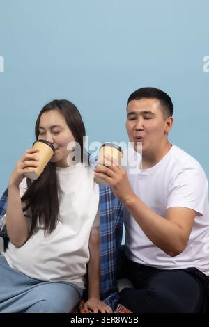 Fröhliches junges glückliches Paar, das heiße Getränke aus Pappbechern zusammen trinkt Stockfoto